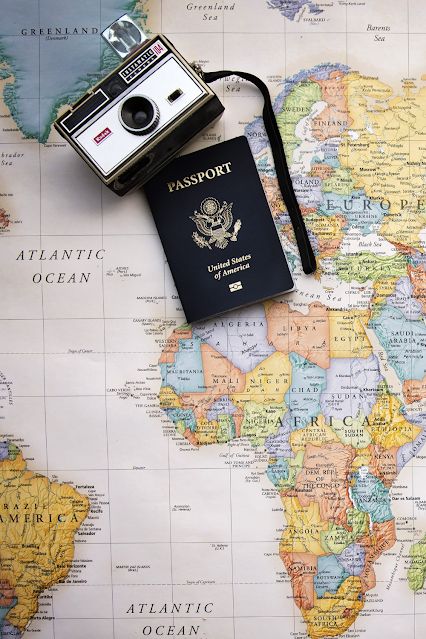 an old camera and passport sitting on top of a map