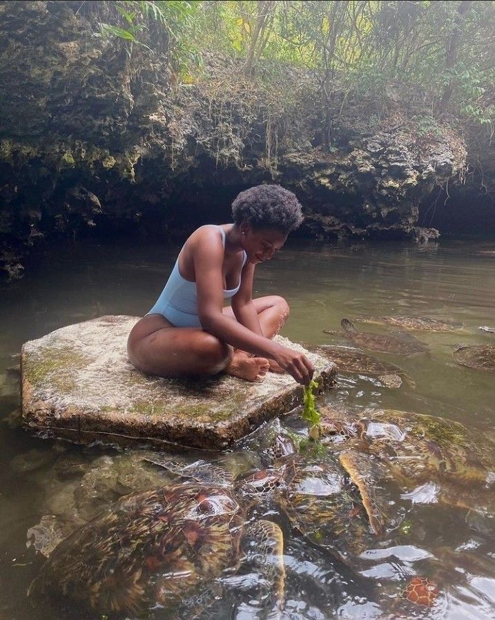 a woman sitting on top of a rock in the water