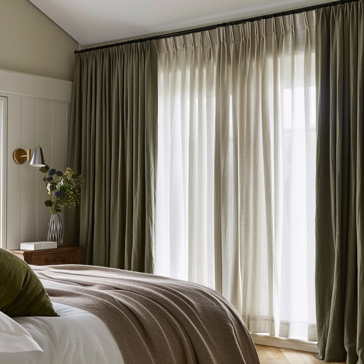 a bedroom with green curtains and a bed in front of a window that has white drapes