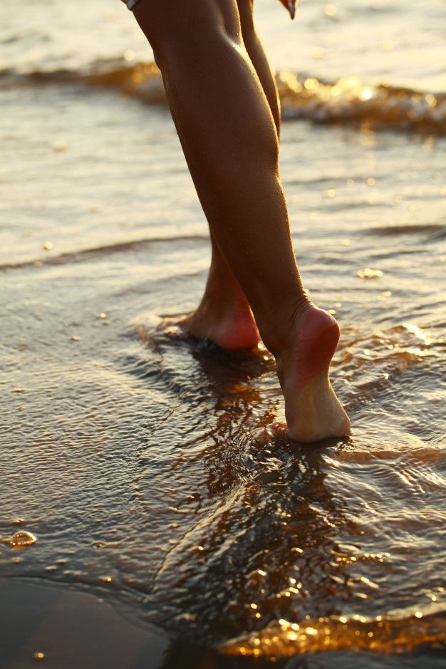 a person walking on the beach with their feet in the water