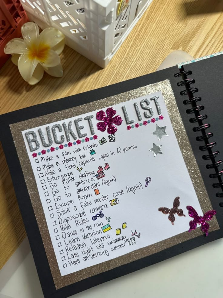 a bucket list is shown in a binder on a desk with flowers and other items