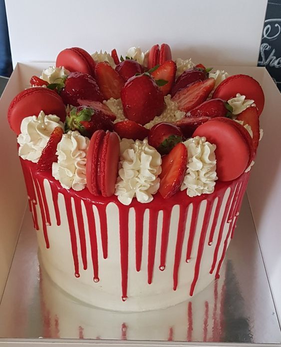 a strawberry cake with white icing and strawberries on top, sitting in a box