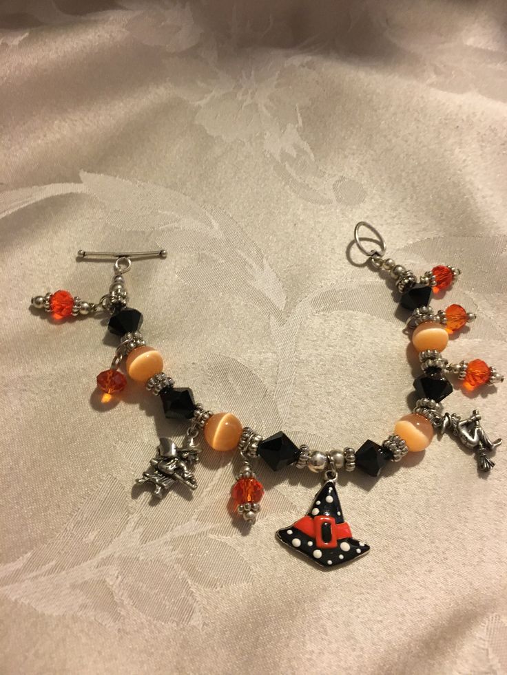 SCARY WITCH CHARM BRACELET.              Very cute bracelet for Halloween. It is 7 1/2 inches long, bracelet has 6  11mm black bicone beads, 4, 11mm cat eyes orange beads.  The charms are two flying witches 20mm in length, 1 witch hat 30mm in length.It also has 6, 9mm round crystal orange beads. The closure is a heart toggle. It is very appropriate for the Halloween season. Witch Bracelet, Long Bracelet, Scary Witch, Flying Witch, Cat Eyes, Cute Bracelets, Halloween Season, Witch Hat, Charm Bracelets