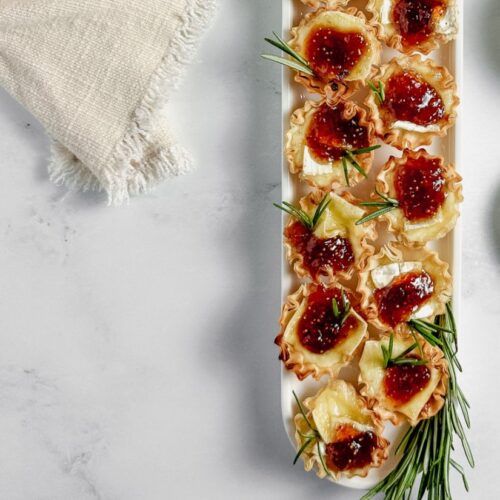 an appetizer is served on a platter with cranberry sauce and rosemary