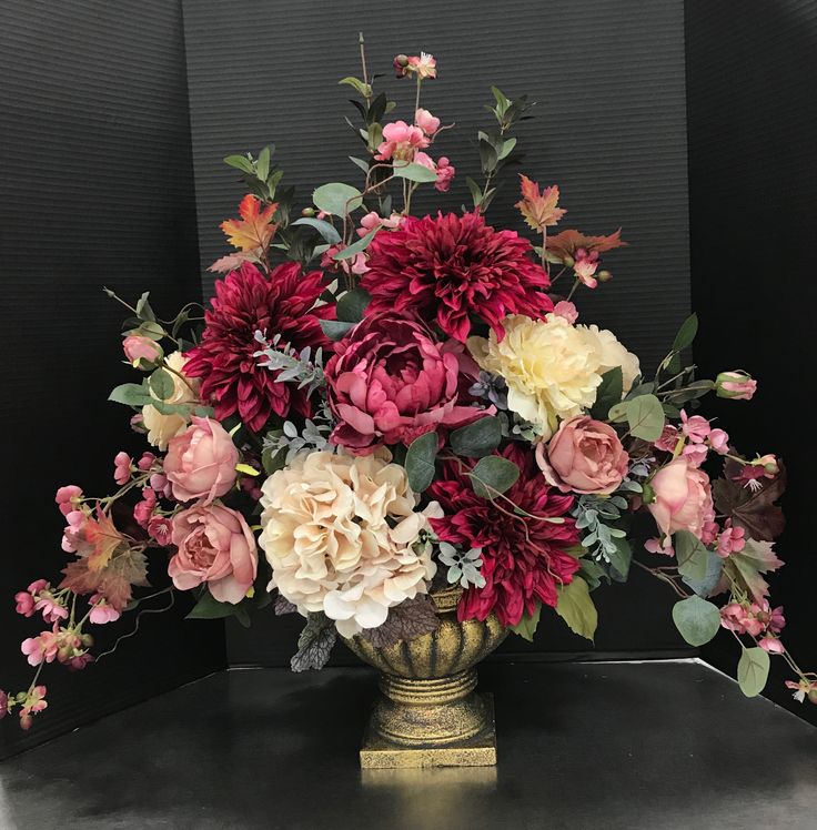 a vase filled with lots of flowers sitting on top of a black table next to a wall