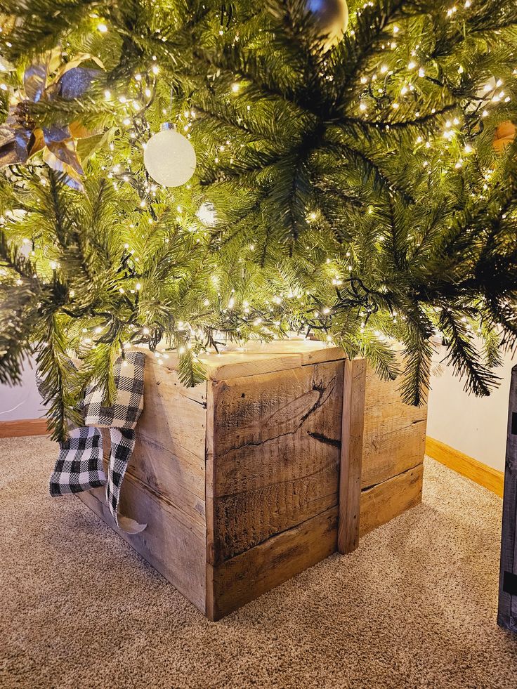 a wooden crate under a christmas tree with lights