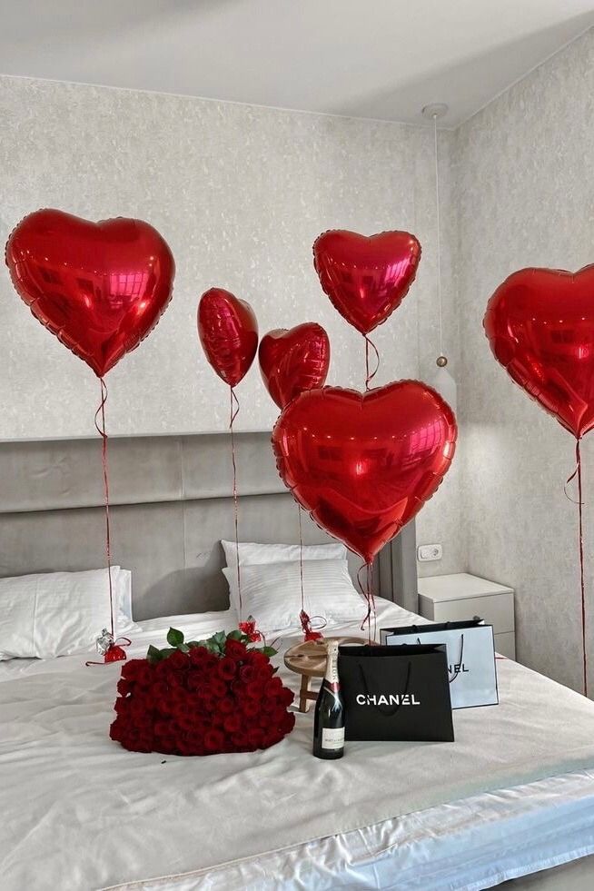 red heart shaped balloons are on the bed