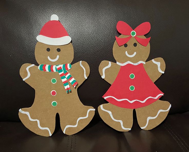 two cut out gingerbread man and woman standing next to each other on a couch