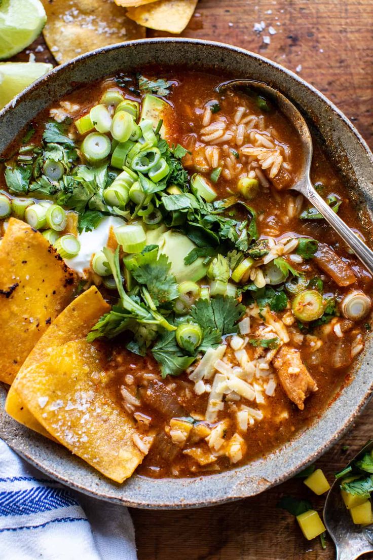 a bowl of mexican soup with tortilla chips and avocado on the side