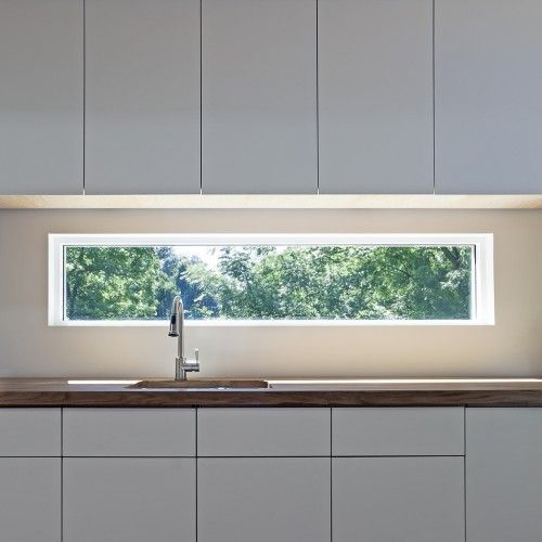 a kitchen with white cabinets and a window above the sink that is lit by lights