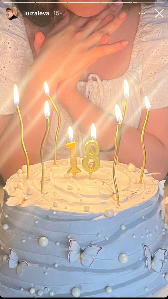 a woman holding a baby in front of a cake with lit candles on it,