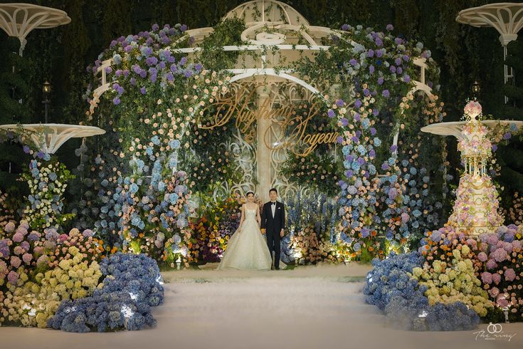 a bride and groom standing in front of an elaborate floral archway at their wedding ceremony