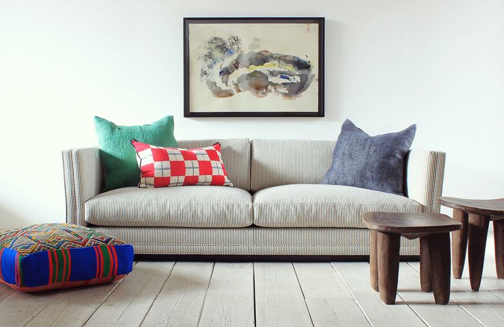 a living room filled with furniture and pillows on top of wooden flooring next to a painting