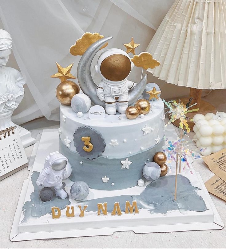 a birthday cake with an astronaut on the moon and stars around it, surrounded by other decorations