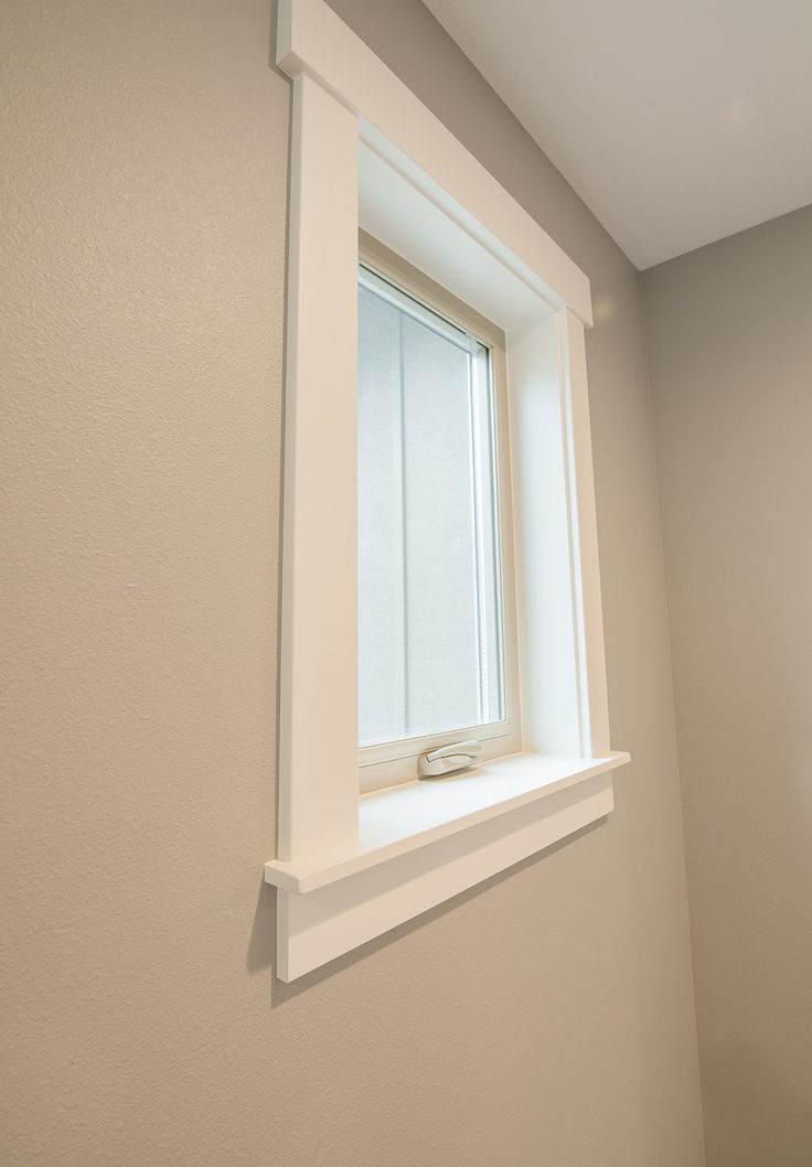 a bathroom with a toilet and window in the corner on the wall, along with a towel dispenser