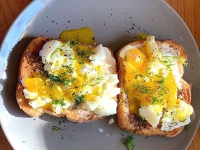 two pieces of bread with an egg and cheese on them sitting on a white plate