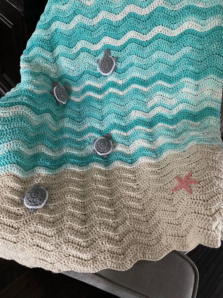 a crocheted blanket with buttons and waves on the bottom is sitting on a chair