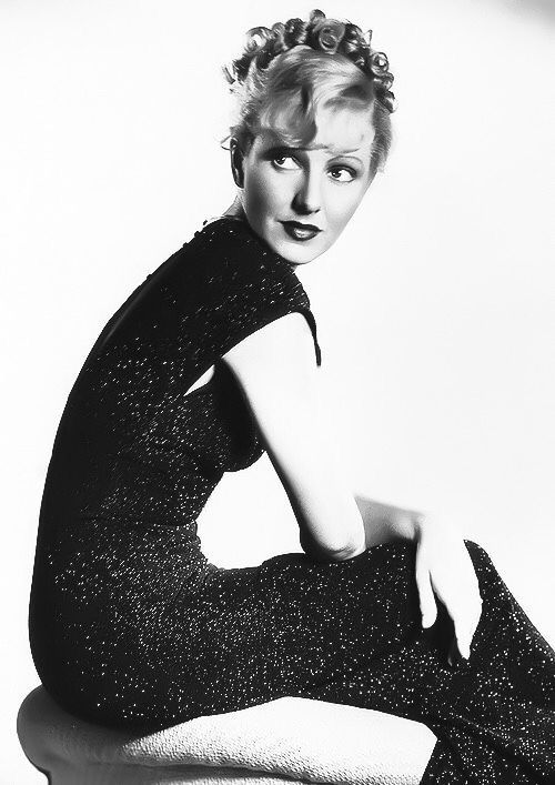 a black and white photo of a woman sitting on a stool