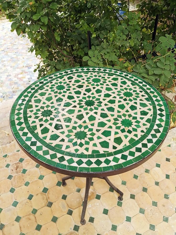 a green and white table sitting on top of a tiled floor next to a tree