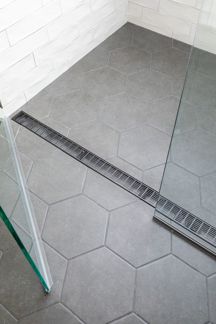 a shower grate sitting on top of a tiled floor next to a glass door