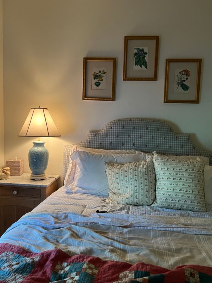 a bed with two lamps on either side of it and pictures above the headboard