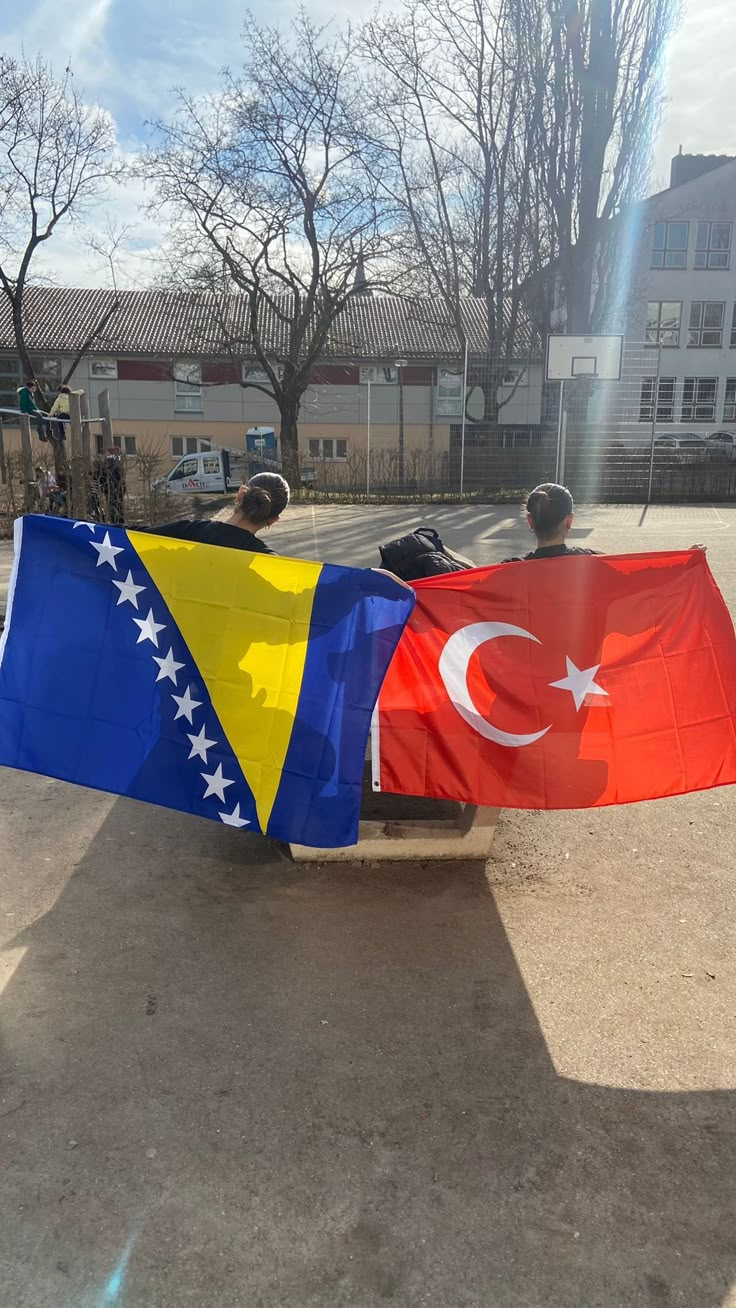 two people sitting on a bench holding flags