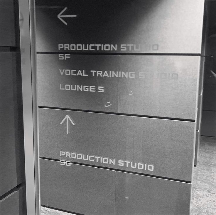 a black and white photo of a sign in an office building that says production studio vocal training lounge