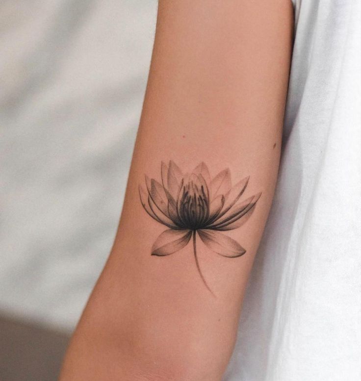 a woman's arm with a black and white flower tattoo on her left arm