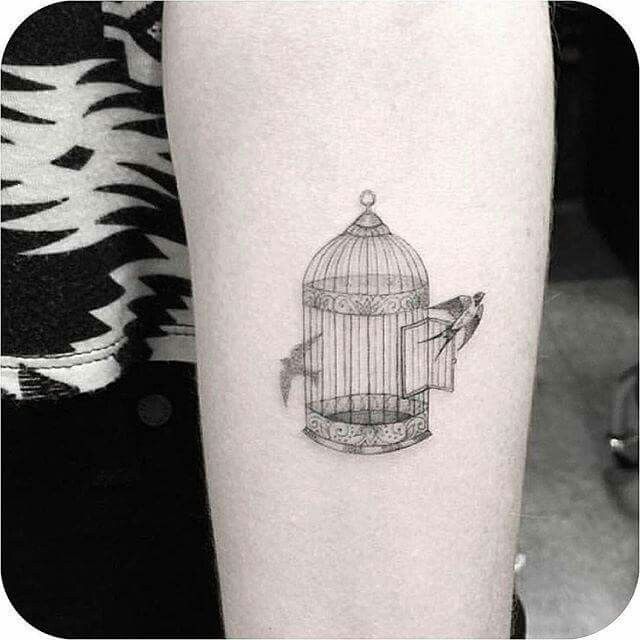 a bird in a cage tattoo on the arm