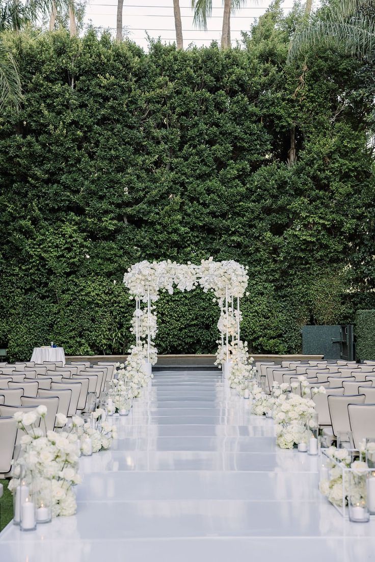 an outdoor ceremony setup with white flowers and greenery