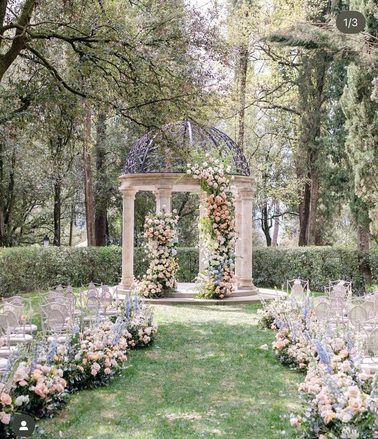 an outdoor ceremony setup with flowers and greenery on the ground, surrounded by trees