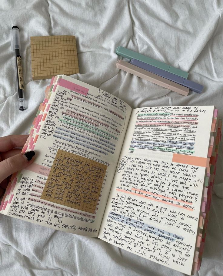 an open notebook with writing on it and some sticky notes in the pages next to a pen