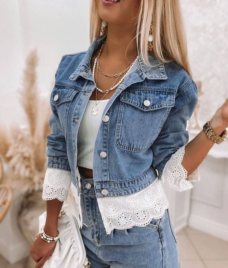 a woman wearing a denim jacket and shorts with white lace trimmings on the sleeves