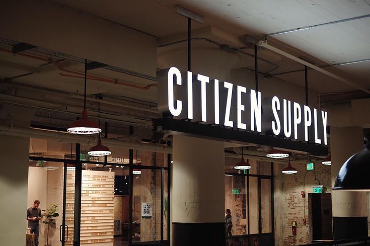 the sign for citizen supply is lit up in an empty room with lots of windows