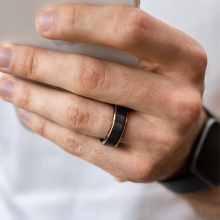 a person wearing a ring on their left hand holding a cell phone in his right hand