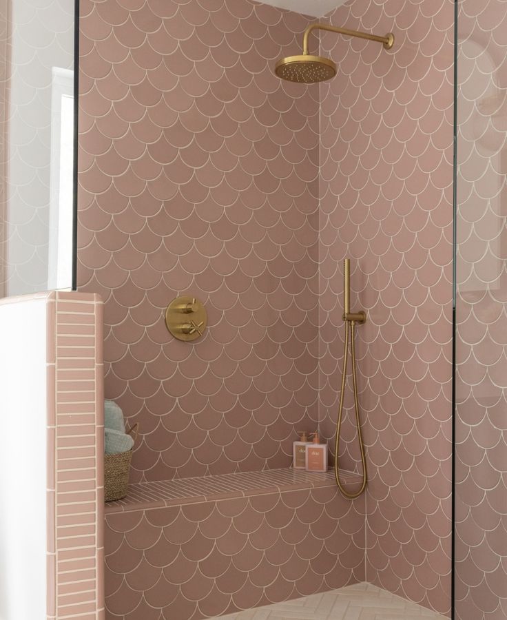 a bathroom with pink wallpaper and gold fixtures, including a walk - in shower