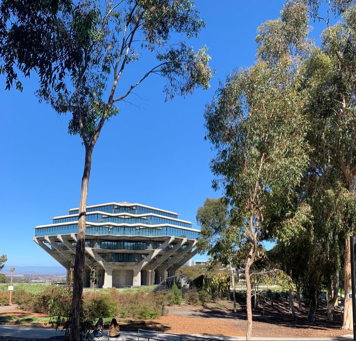 a large building surrounded by trees on a sunny day