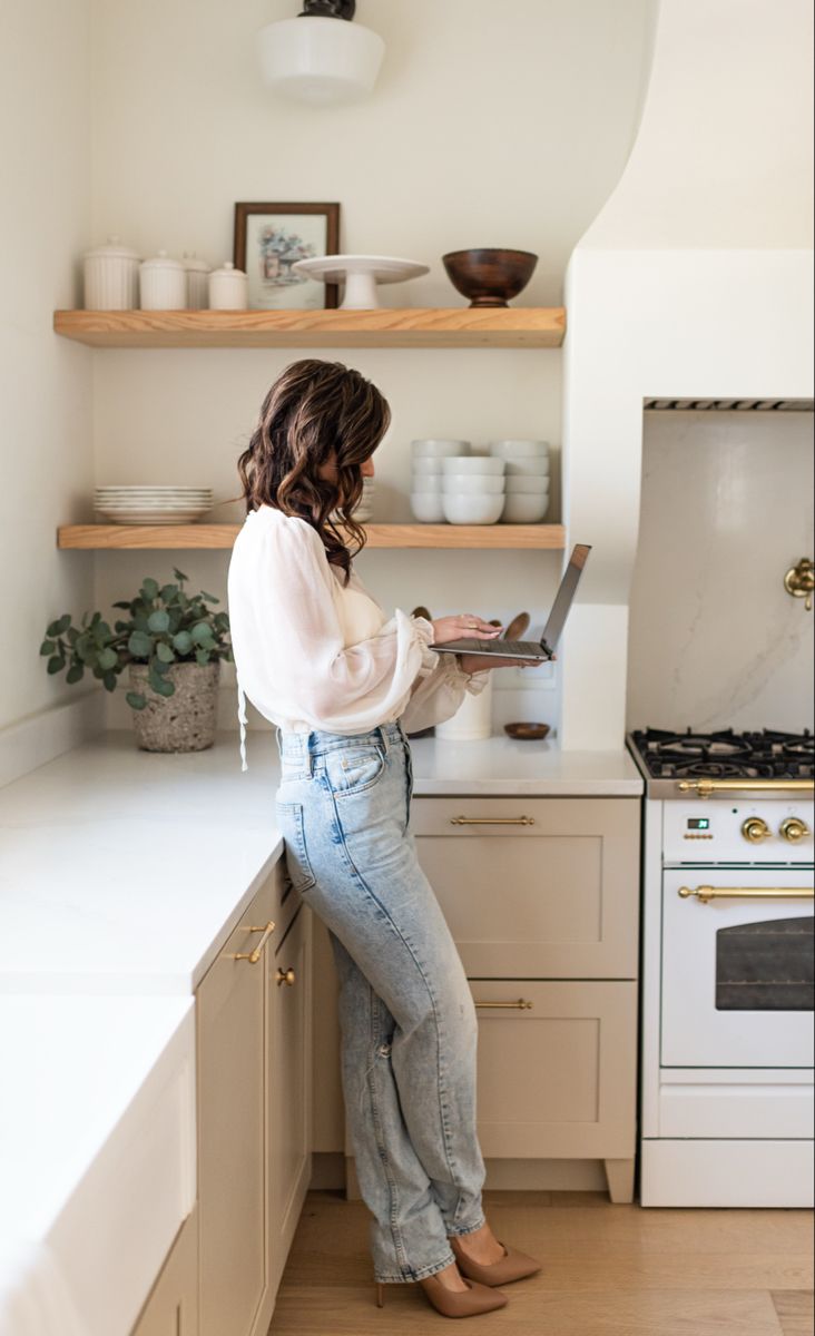 a woman standing at the kitchen counter using her laptop