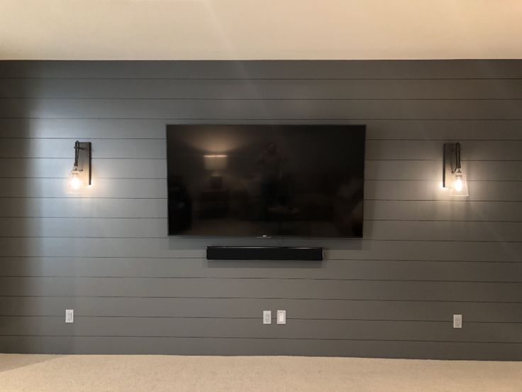 a flat screen tv mounted to the side of a wall in a room with gray walls