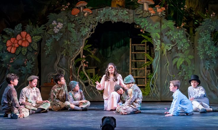 children sitting on the ground in front of a stage