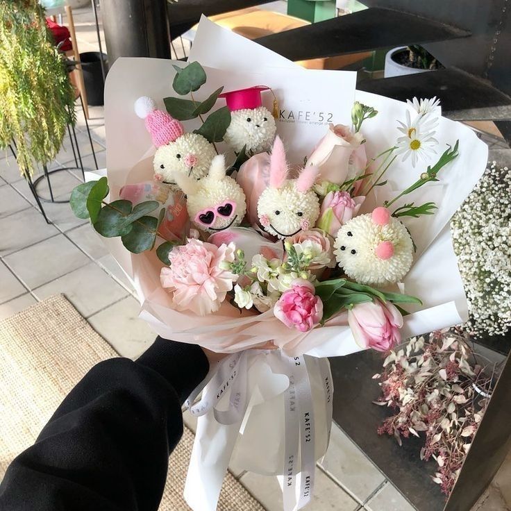 a bouquet of flowers and stuffed animals is being held by a person's hand