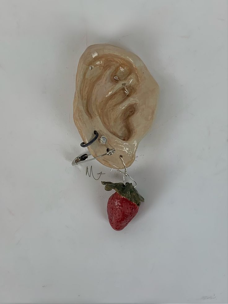 a sculpture of a human head with a strawberry in front of it on a white surface