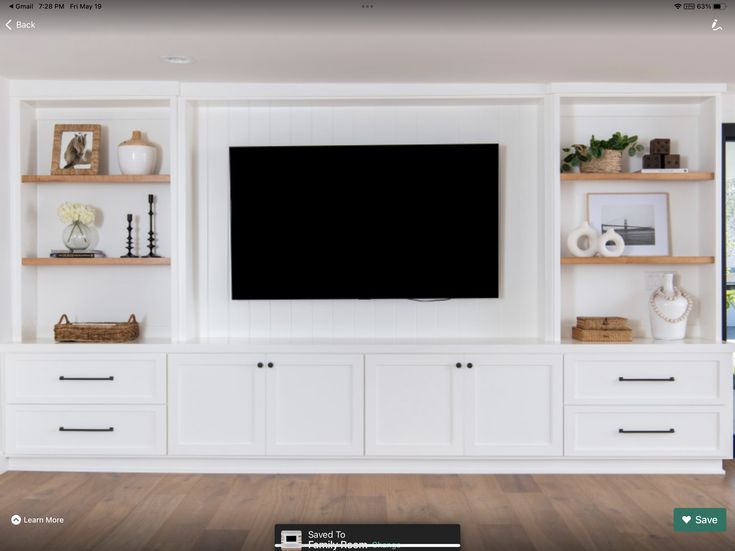 a large flat screen tv mounted to the side of a white entertainment center in a living room