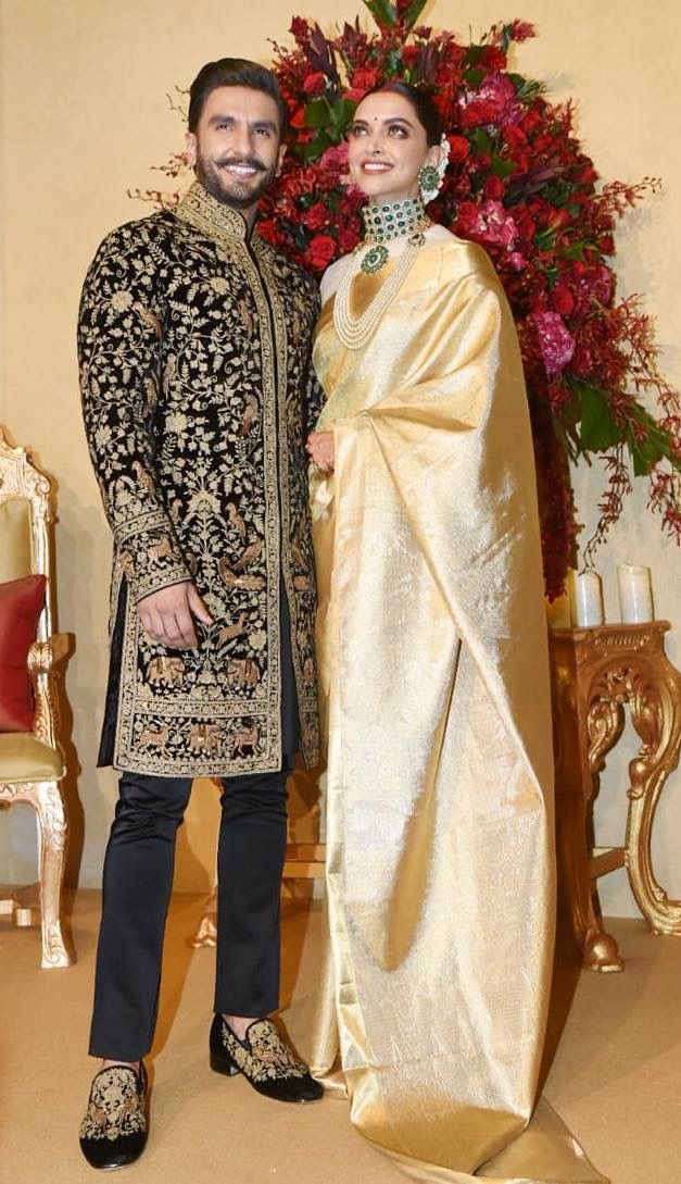 a man and woman standing next to each other in front of a floral arrangement with red flowers