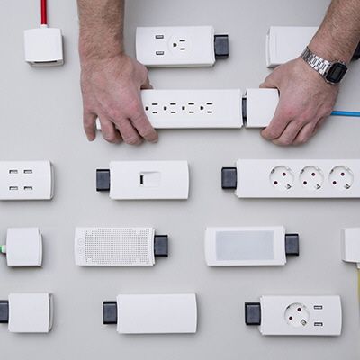 several different types of electrical plugs are arranged on a table with one person's hands