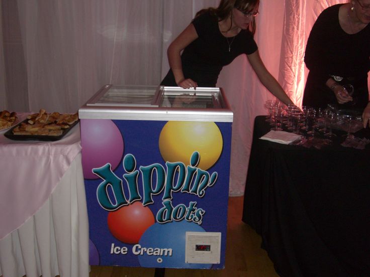 two people standing at a table with food on it and a sign that says sippin'dots ice cream