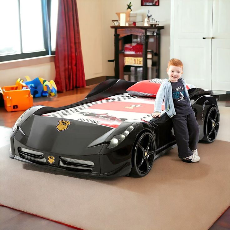 a little boy standing next to a race car bed