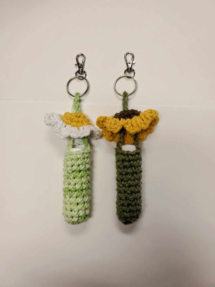 two crocheted vases with flowers are hanging from key chains on a wall