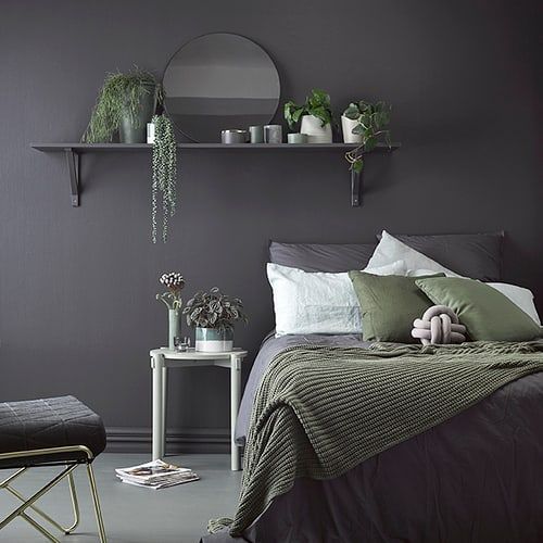 a bed room with a neatly made bed next to a shelf filled with potted plants