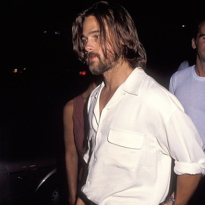 a man with long hair and beard standing next to another man in a white shirt